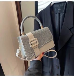 Detail of grey crossbody bag with shimmering rhinestone cover and silver buckle closure