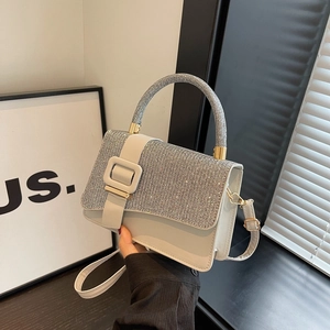 Detail of silver rhinestone handbag with glossy white finish and metallic chain strap