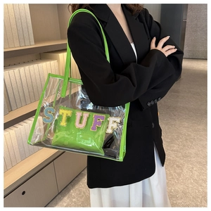 Detailed view of transparent PVC tote bag with neon green edges and STUFF glitter letter patches