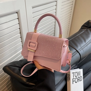 Detailed shot of pink glitter handbag with golden buckle and textured top handle on sofa