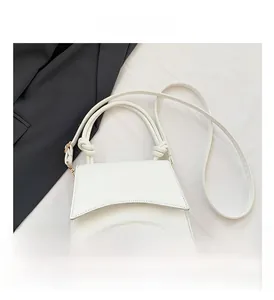 Detail of white leather trapezoid handbag with decorative knot and gold hardware