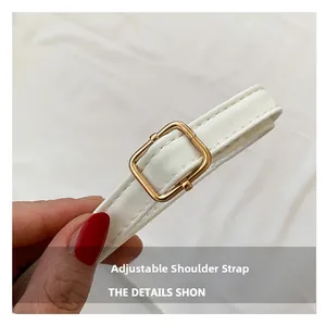 Close-up of white leather adjustable shoulder strap with golden metal pin buckle