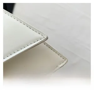 Detail showing high-quality lychee grain leather texture and neat stitching on a white bag