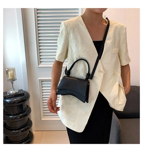 Chic black structured handbag with curved base and knot detail on the handle in studio setting