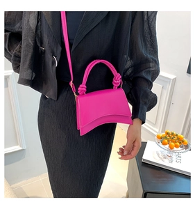 Detail of rose pink hourglass bag with curved base and twisted rope handle accent