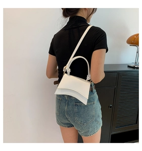 Close-up of white leather hourglass handbag with unique curved base and knotted handle detail