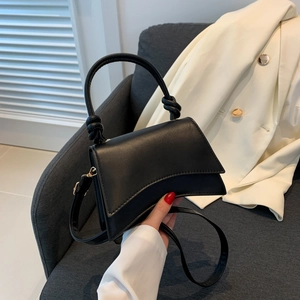 Detail of the unique knotted handle and smooth matte leather on black minimalist bag