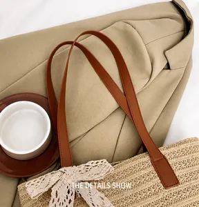 Detail view of woven straw tote with brown leather strap and delicate lace bow accent
