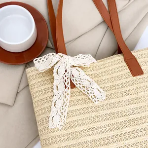 Detail of straw woven bucket bag featuring white lace bow and brown leather strap