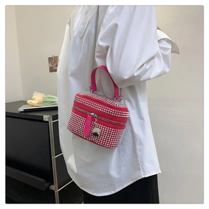Détail du sac fuchsia avec strass et bandoulière chaîne sur une chemise blanche