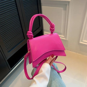 Fashionable bright pink leather handbag with curved base and large knot handle detail