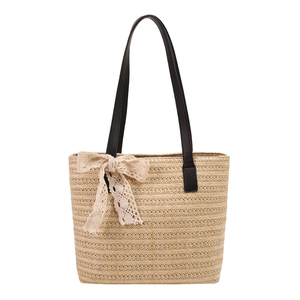 Straw tote bag with lace bow decoration and black shoulder strap on white background