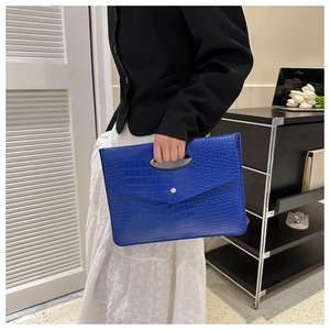 Dettaglio borsa blu reale con trama a coccodrillo e chiusura metallica rotonda