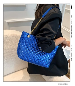 Electric blue quilted tote bag with metallic chain strap worn by model over black blazer