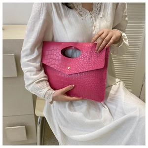 Dettaglio della borsa rosso rosa con motivo a coccodrillo, manico traforato e bottone oro
