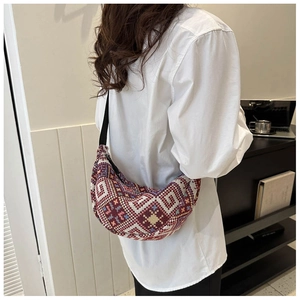 Detail of bohemian geometric woven sling bag with colorful rhombus patterns on a model
