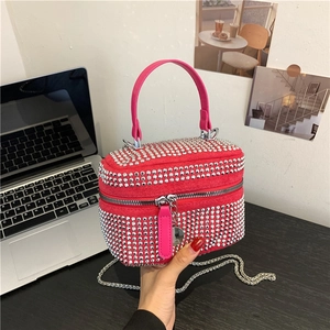 Sac à main strass rouge avec anse rose et bandoulière chaîne dans un bureau élégant