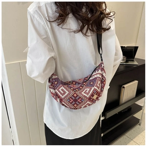 Ethnic jacquard crescent shoulder bag with colorful geometric patterns shown on a model