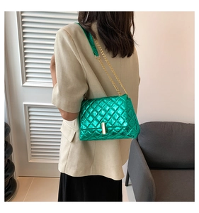 Close-up of metallic green quilted bag with gold rectangle clasp and chain strap