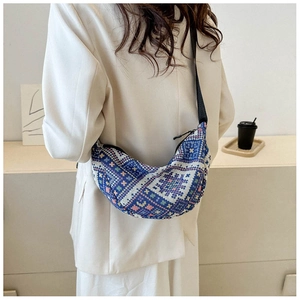 Close-up of ethnic jacquard crescent bag worn with a white blazer for urban commuting