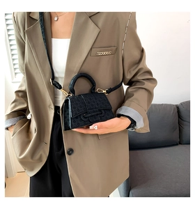 Detail of black geometric embossed small square handbag with gold hardware and top handle