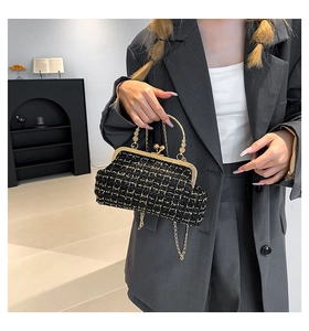 Detail of elegant black and gold tweed handbag with vintage clasp and metal handle