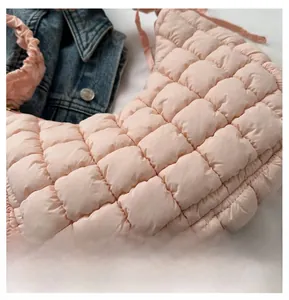Détail du sac croissant matelassé rose avec poignée plissée sur fond en denim