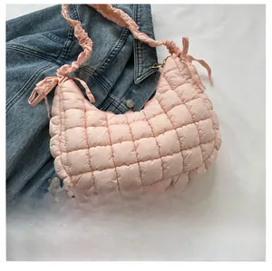 Détail du sac bulle matelassé rose avec bandoulière plissée sur fond en jean bleu