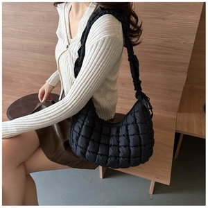 Detail of a black quilted puffer bag with chic pleated straps and soft cloud texture