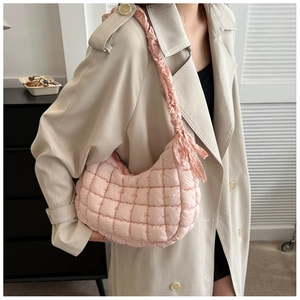 Side view of a pink quilted bubble shoulder bag with ruffle strap and bow detail