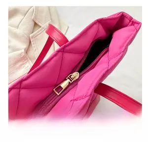 Close-up of smooth golden metal zipper and quilted diamond pattern on pink tote bag