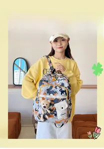 Detail view of floral backpack with camo print, front pocket, and plush bear charm accessory
