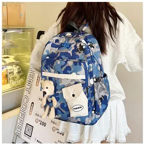 Detail of blue floral backpack with white flap pocket and bear charm on back of model