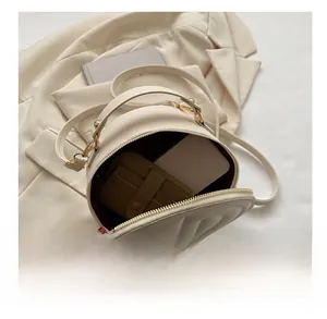 Detailed capacity view of the beige round handbag with card holder and smartphone inside
