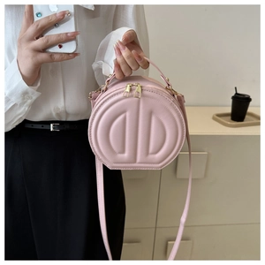 Close-up of pink round crossbody bag featuring double D quilted texture and gold hardware