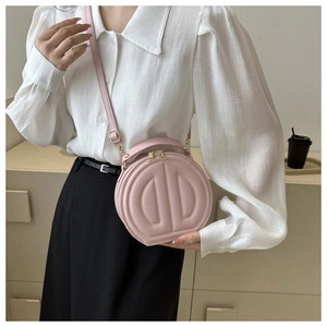Detailed macro view of pink round crossbody bag featuring embossed D letter and gold zipper