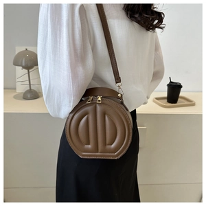 Brown circular crossbody bag featuring textured D-shaped embossing and gold hardware