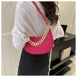 Detail of rose pink crescent bag with thick gold chain and matte texture on model