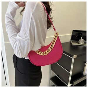 Detail of bright pink faux crocodile leather shoulder bag with decorative gold chain