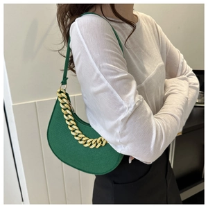 Detailed close-up of a vibrant green crescent shoulder bag with a bold gold chain link