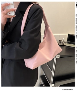 Close-up of light pink nylon crescent bag worn underarm in an urban office setting