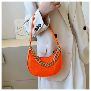 Detail of bright orange crocodile texture crescent bag with gold chain strap decoration