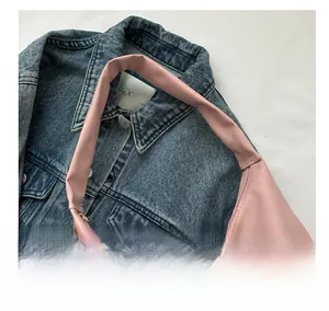 Pink nylon tote bag detail with wide comfortable handles on denim background