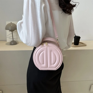 Chic pink circular crossbody bag with embossed D design and gold-tone hardware detail