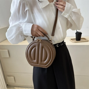 Brown circular crossbody bag with 3D D-shaped embossing and golden zipper details