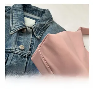 Detail view showing precise stitching on pink leather crossbody bag over denim