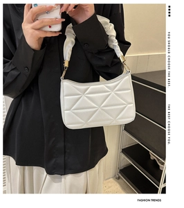 Details der weißen Handtasche mit Falten-Griff, geometrischer Prägung und Goldringen