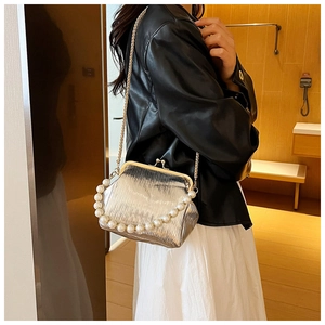 Close-up of silver pleated metallic clutch bag with pearl handle and gold chain detail