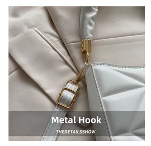 Details goldener Metallhaken an weißer Stepptasche mit gerafftem Schulterriemen