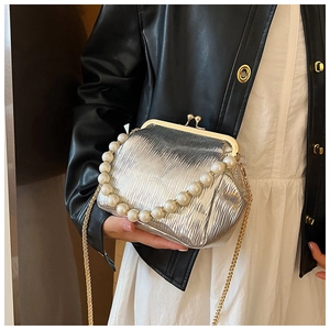 Detail of silver pleated evening bag featuring pearl handle and metallic clasp closure